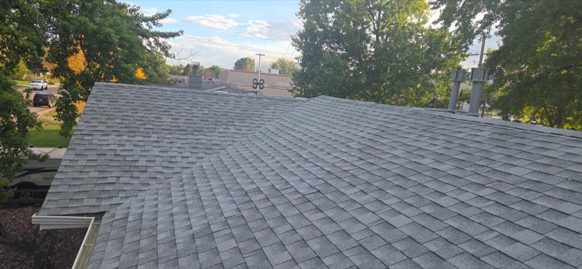 Freshly installed grey architectural shingle roof photographed at dusk