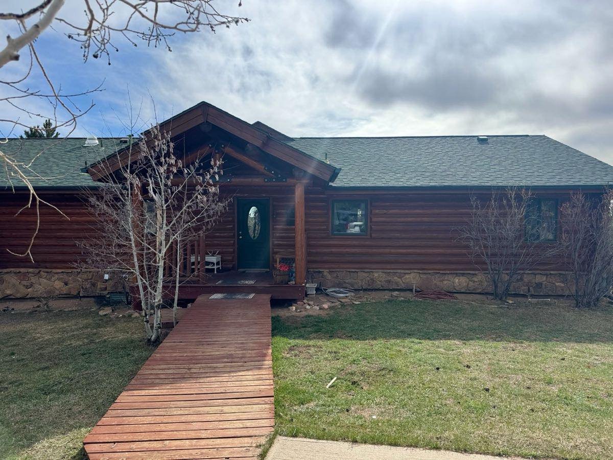 Log home with a new green metal roof installed by Crazy Horse Roofing