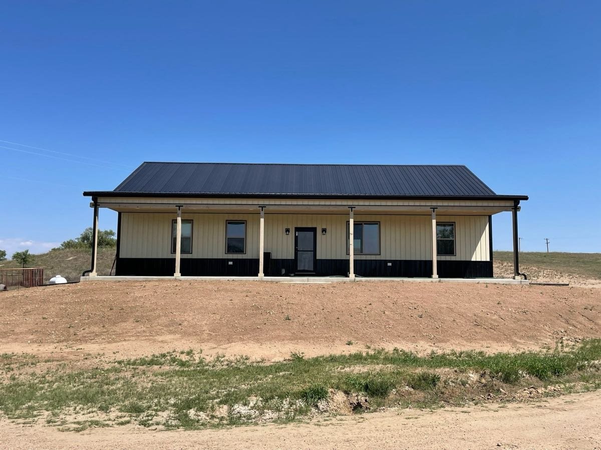 Ranch home with a new black standing seam metal roof and wrap-around porch